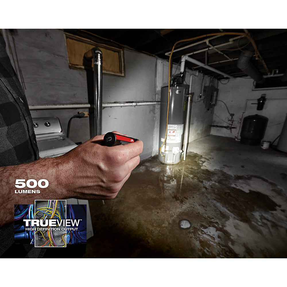 Black and red compact flashlight held in hand, illuminating a basement interior.