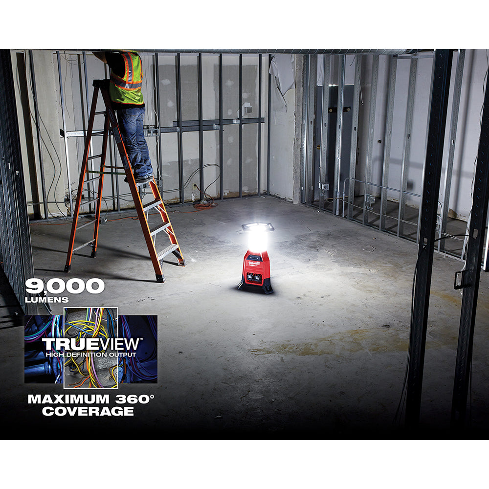 Red and black M18 RADIUS site light illuminating a construction site interior with 360-degree coverage.