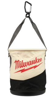 Canvas bucket with cream upper section featuring red Milwaukee logo, black lower section, gray straps, and black carabiner cl