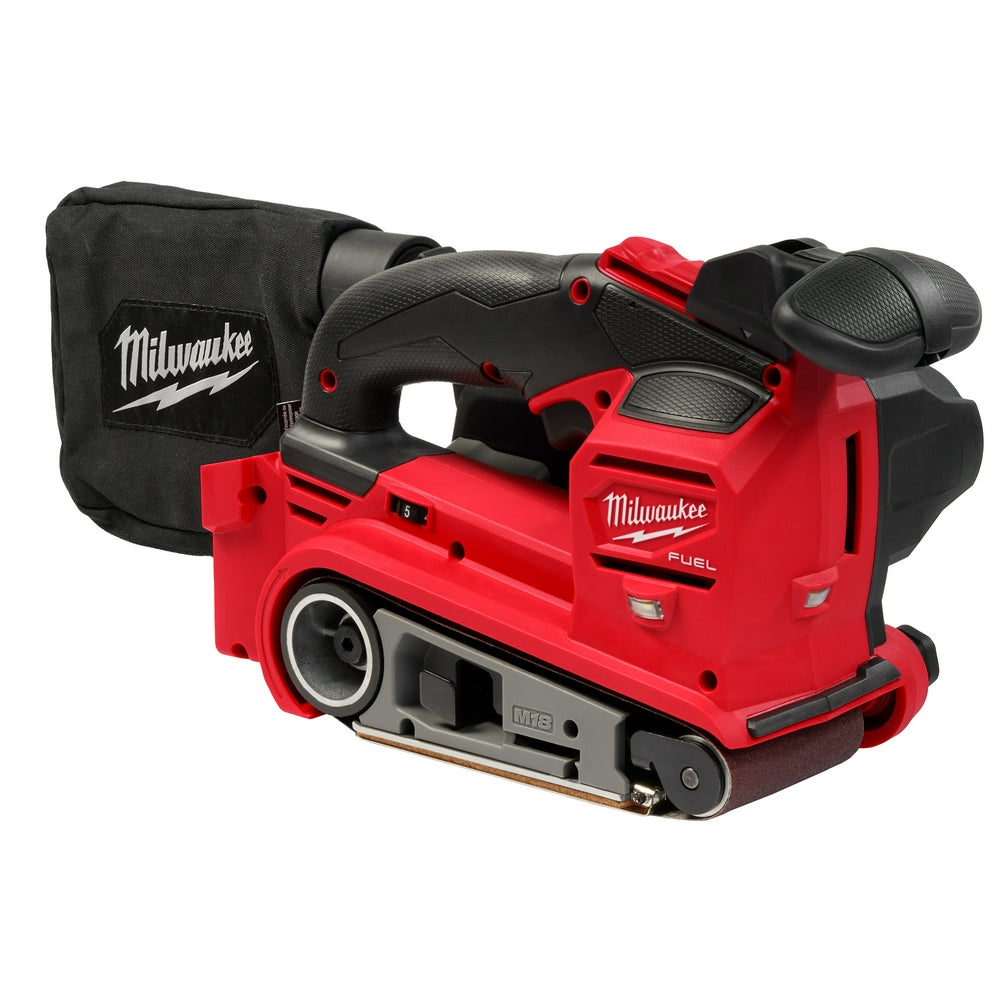 Red and black Milwaukee M18 FUEL belt sander with dual handles, sanding belt visible underneath, and black carrying bag.