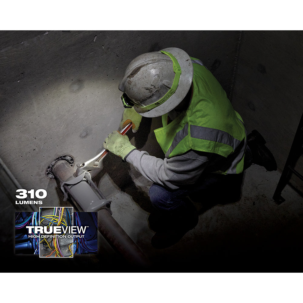 Worker in safety gear using headlamp to inspect dark industrial surface.
