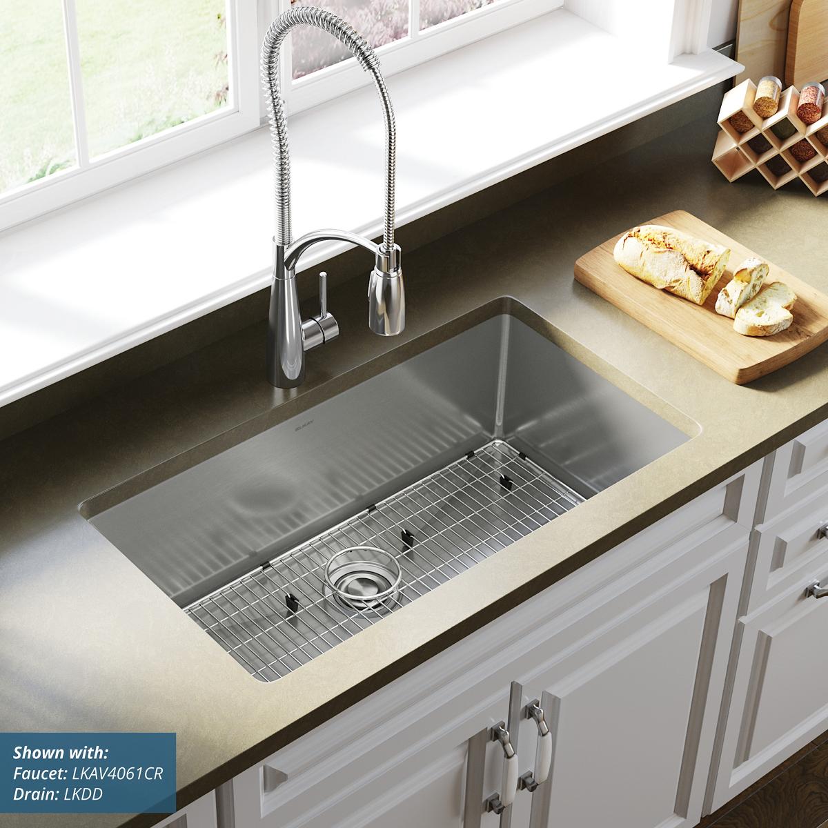 Stainless steel undermount kitchen sink with single bowl, ribbed bottom, and included drain strainer in countertop.
