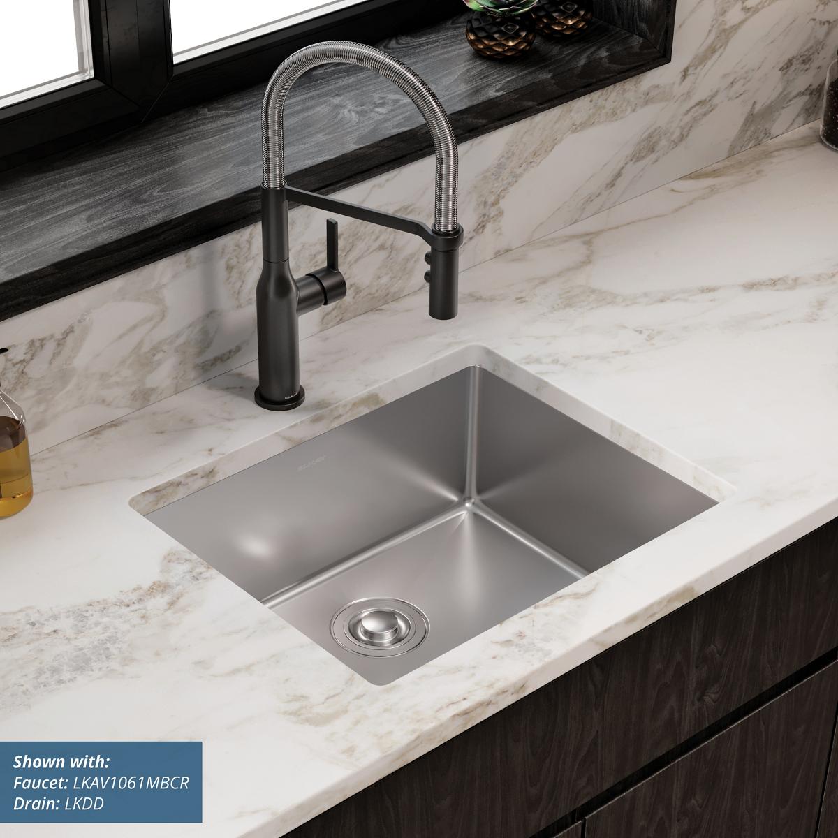 Stainless steel single-bowl undermount sink installed in marble countertop with black pull-down faucet.