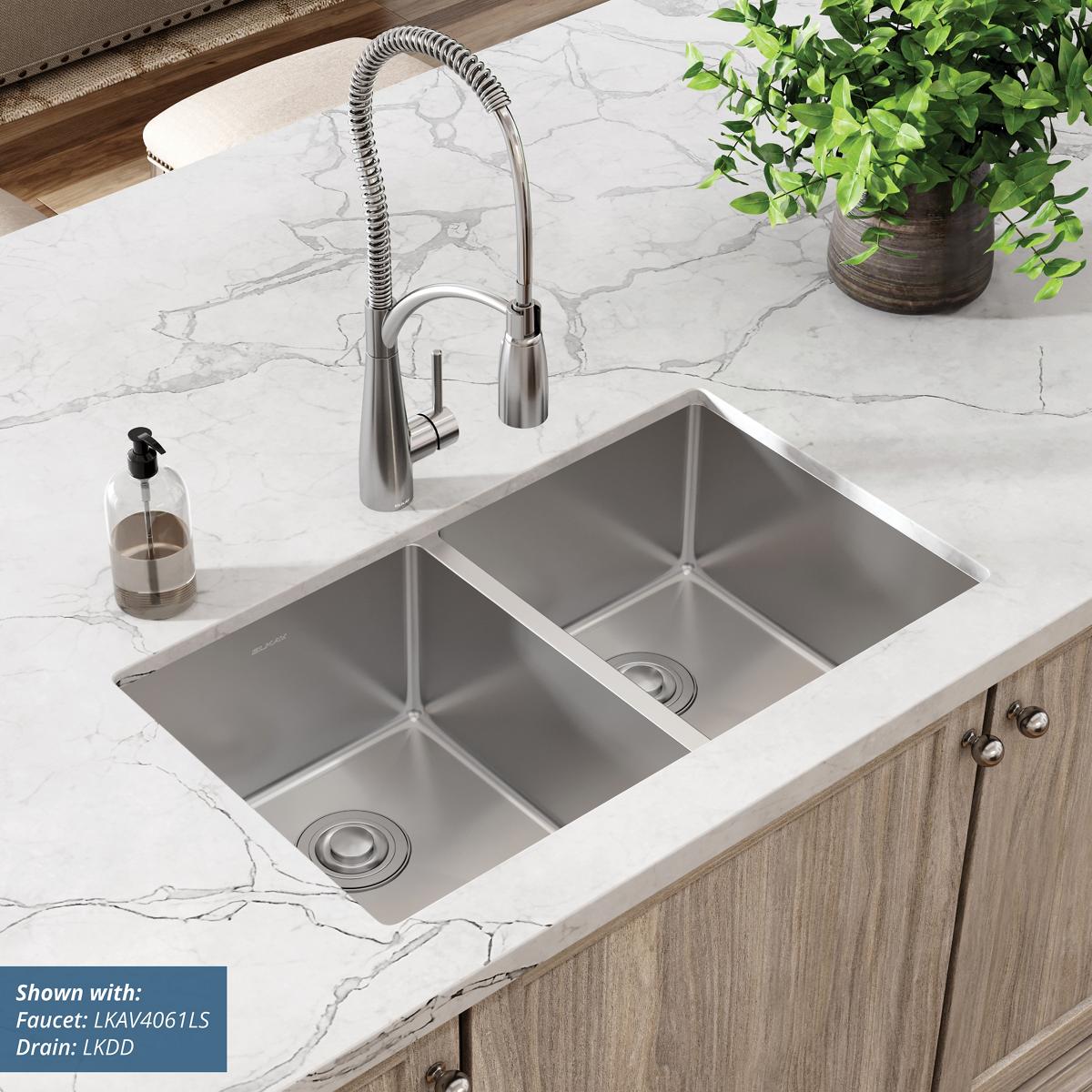 Stainless steel double bowl undermount sink installed in white marble countertop with chrome pull-down faucet.