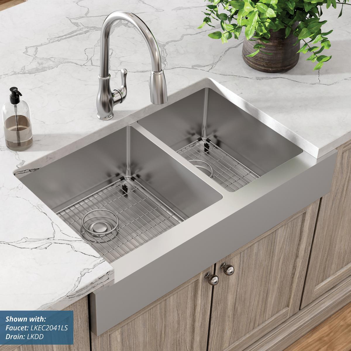 Stainless steel double bowl farmhouse sink with two rectangular basins, metal grids, and pulldown faucet installed in white m