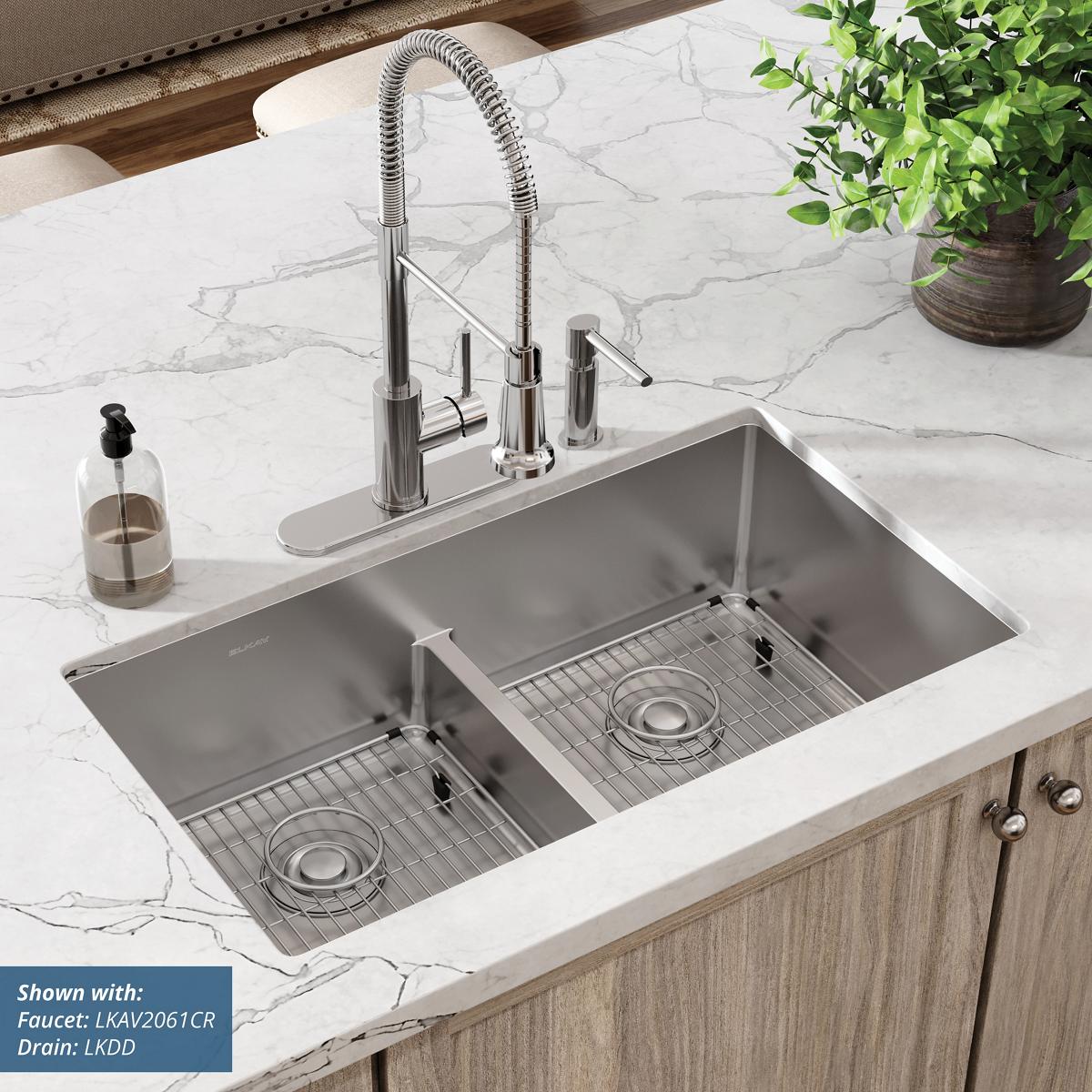 Stainless steel double bowl sink with two equal basins, grid inserts, and chrome pull-down faucet mounted in white marble cou