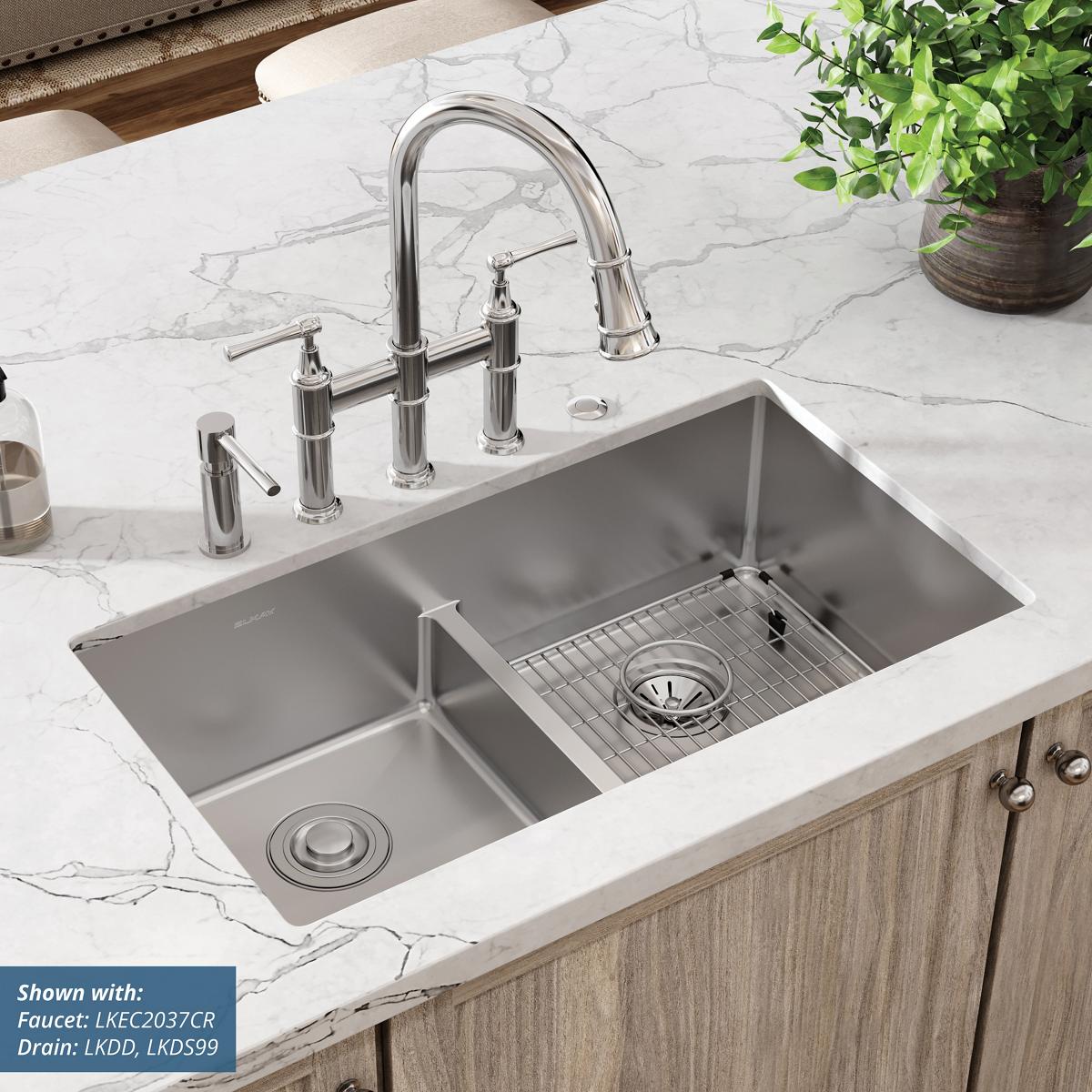 Stainless steel double bowl sink with divider installed in white marble countertop, featuring pull-down faucet and five mount
