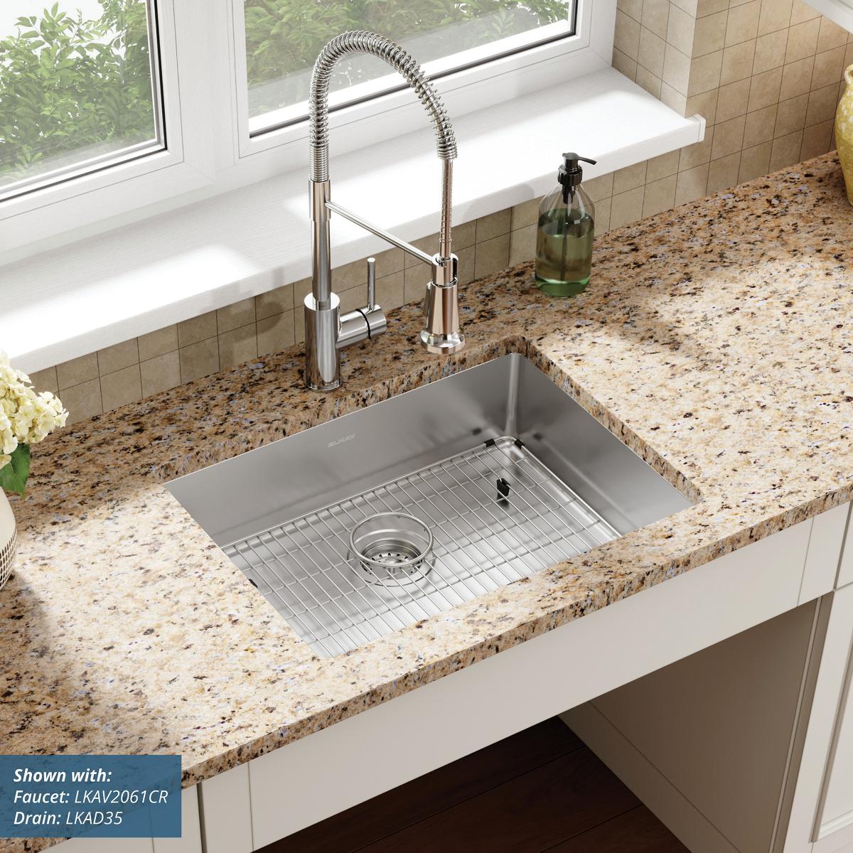 Stainless steel rectangular sink bowl mounted in speckled countertop with single faucet hole and included drain basket.