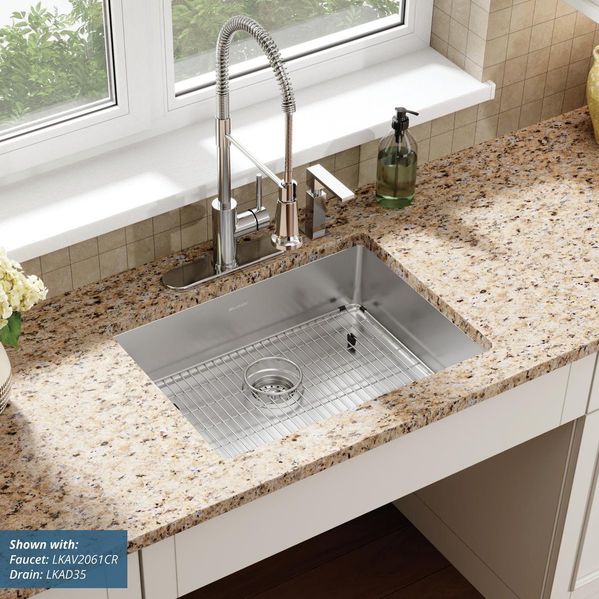 Stainless steel single bowl sink installed in granite countertop with chrome faucet and grid strainer.