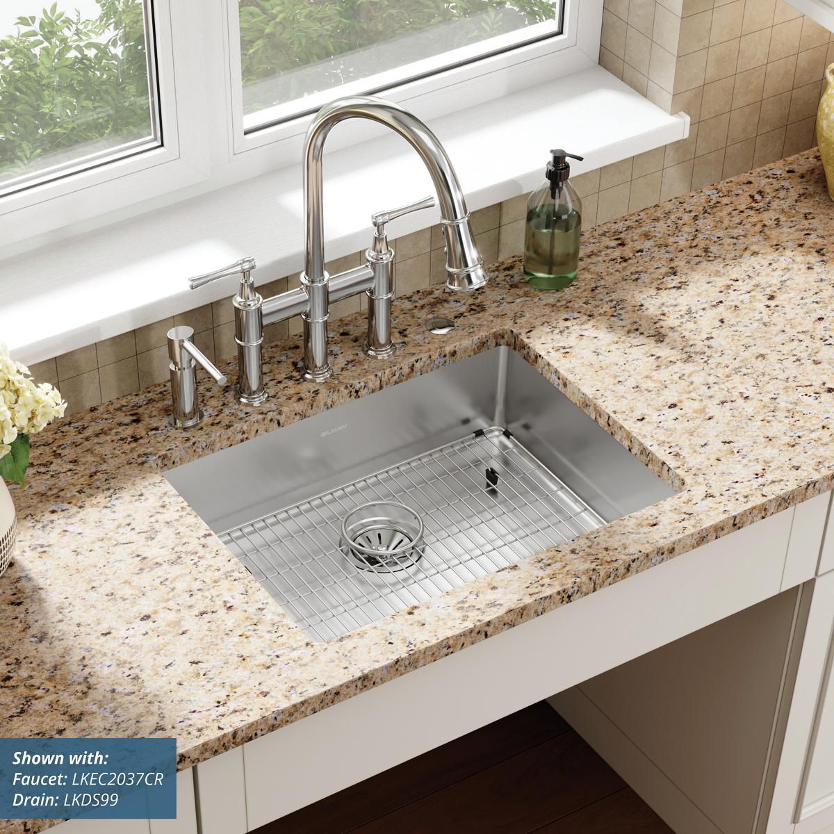 Stainless steel single bowl sink with five holes mounted in speckled granite countertop, includes pull-down faucet and grid s