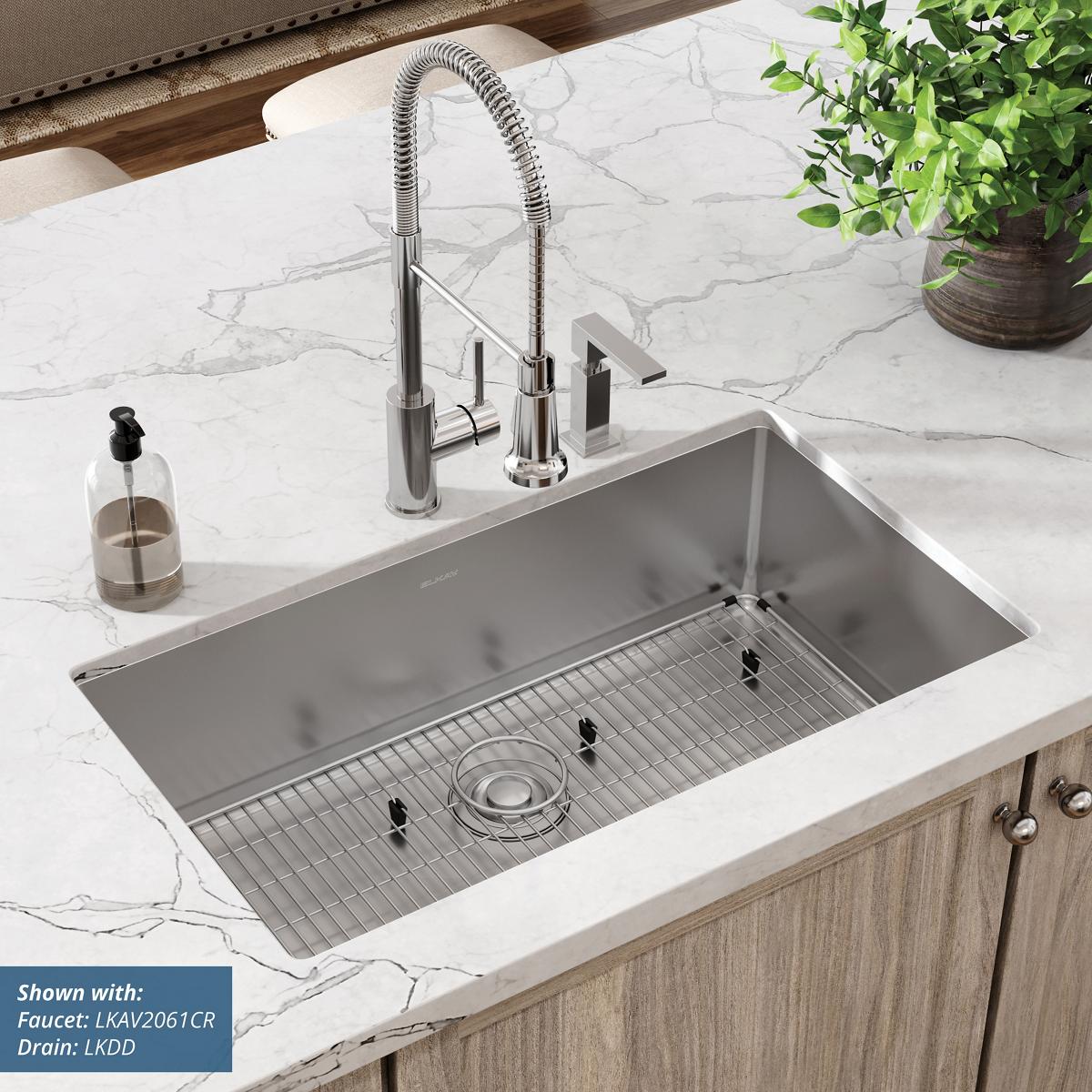 Stainless steel rectangular undermount sink with single bowl, grid rack, and two faucet holes on marble countertop.