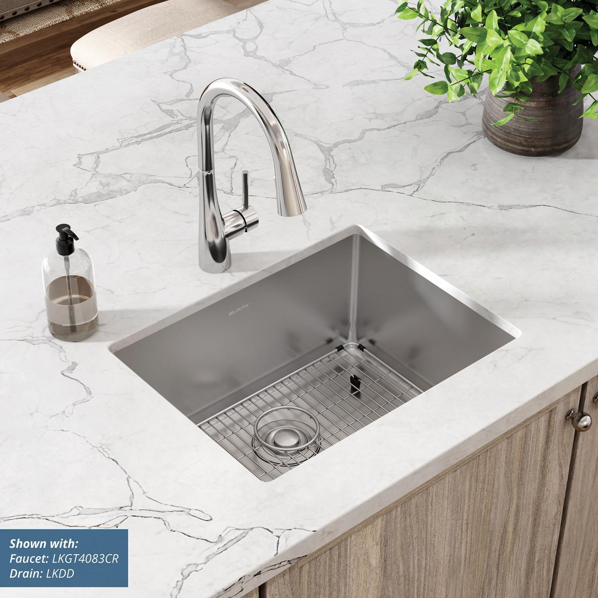 Stainless steel single bowl undermount sink with rounded corners installed in marble countertop, shown with faucet and drain.