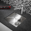 Stainless steel rectangular bar sink with single faucet hole, mounted in dark countertop.