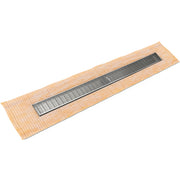 Polished stainless steel linear drain with slotted grate installed on tan tile shower base.