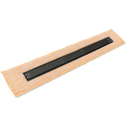 Matte black linear drain with metal grate installed on tan tile floor grid.