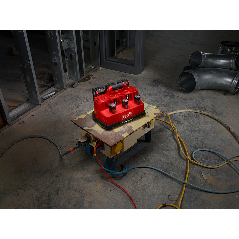 Red Milwaukee rapid charge station with six charging ports mounted on beige base with power cords on concrete floor.