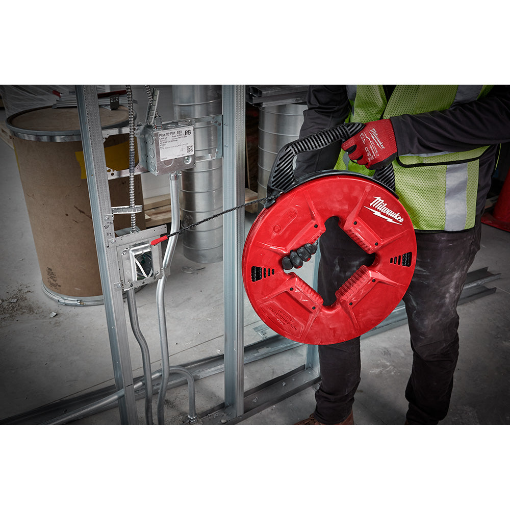 Red polyester fish tape reel with black handle held by worker in safety vest near electrical conduit.