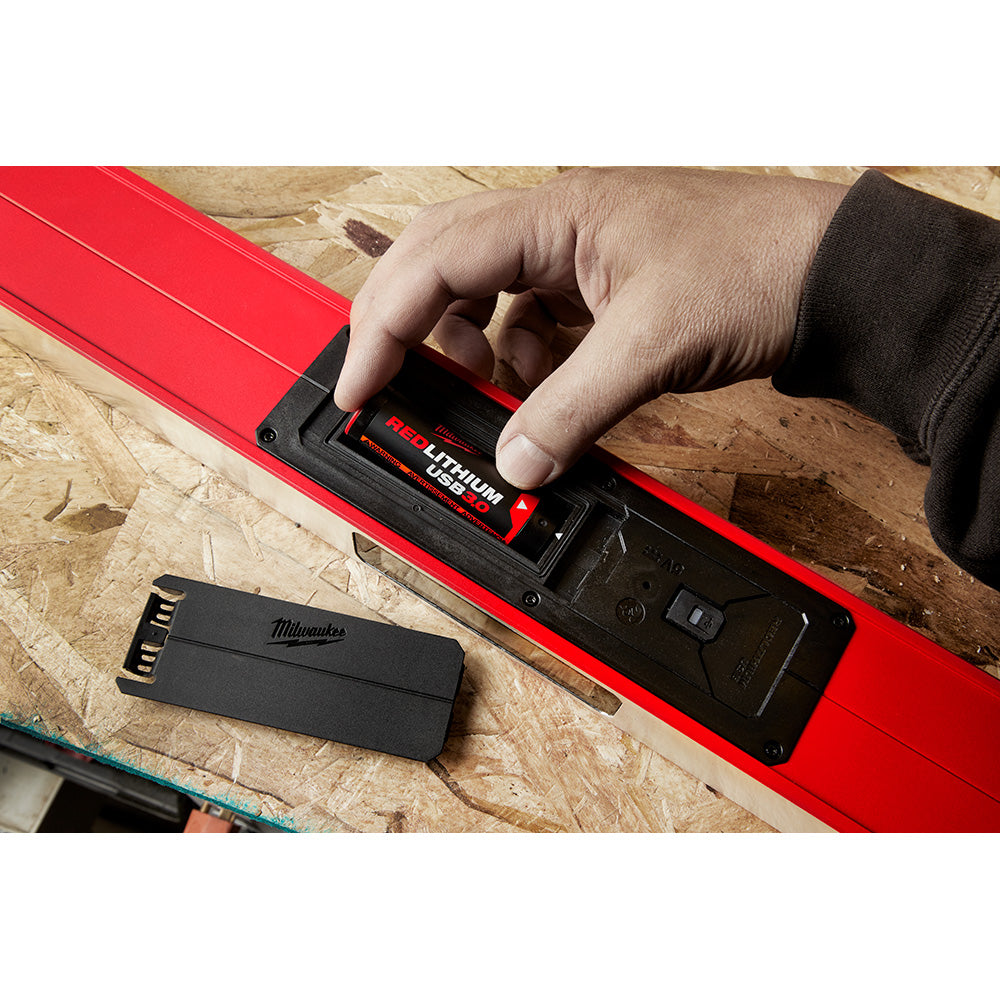 Two red Milwaukee REDLITHIUM USB batteries with black charging ports on wooden work surface.