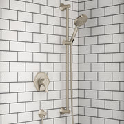 Brushed nickel shower system with wall-mounted valve, vertical bar, and handheld showerhead mounted on white subway tile wall