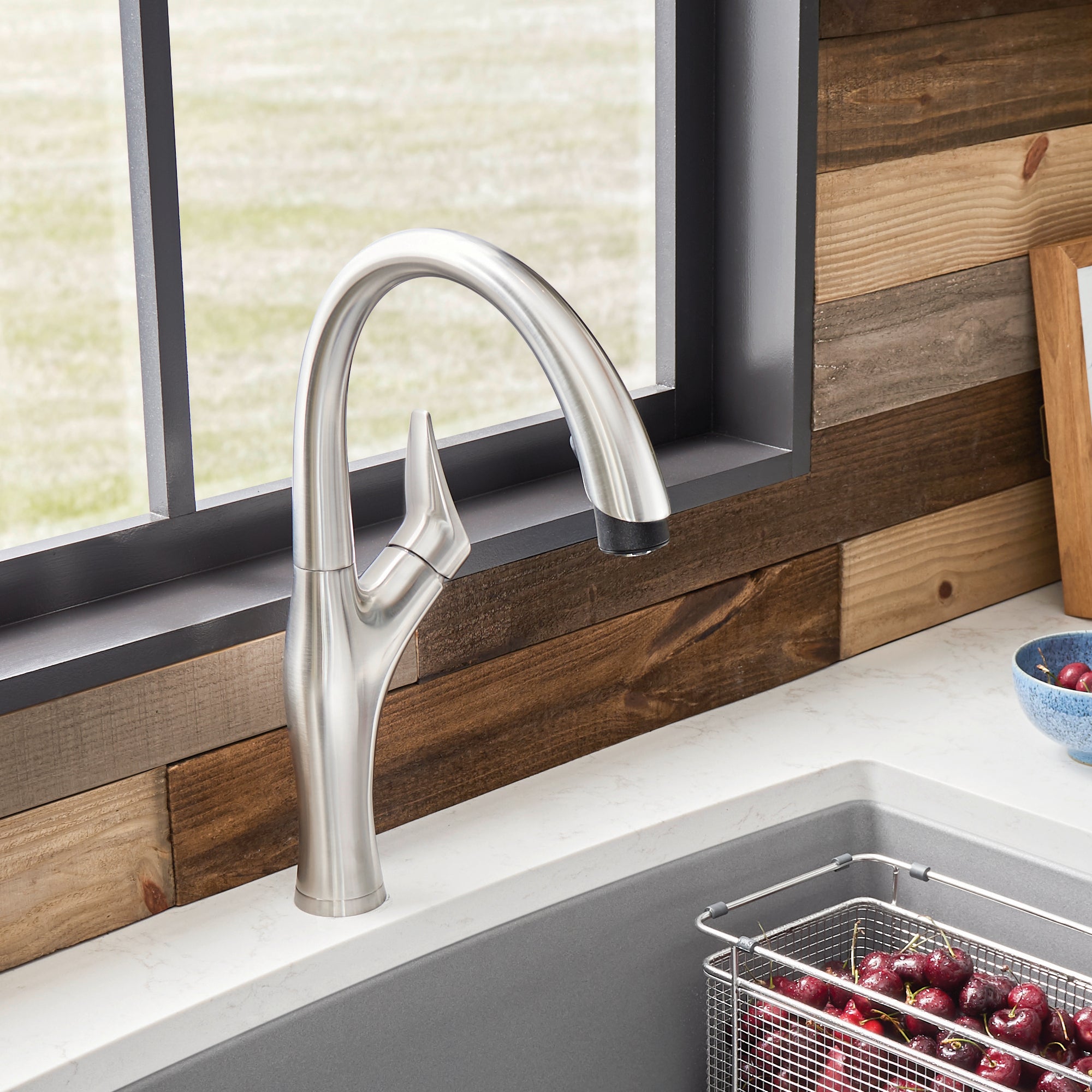 Stainless steel pull-down kitchen faucet with curved spout and lever handle mounted above sink.