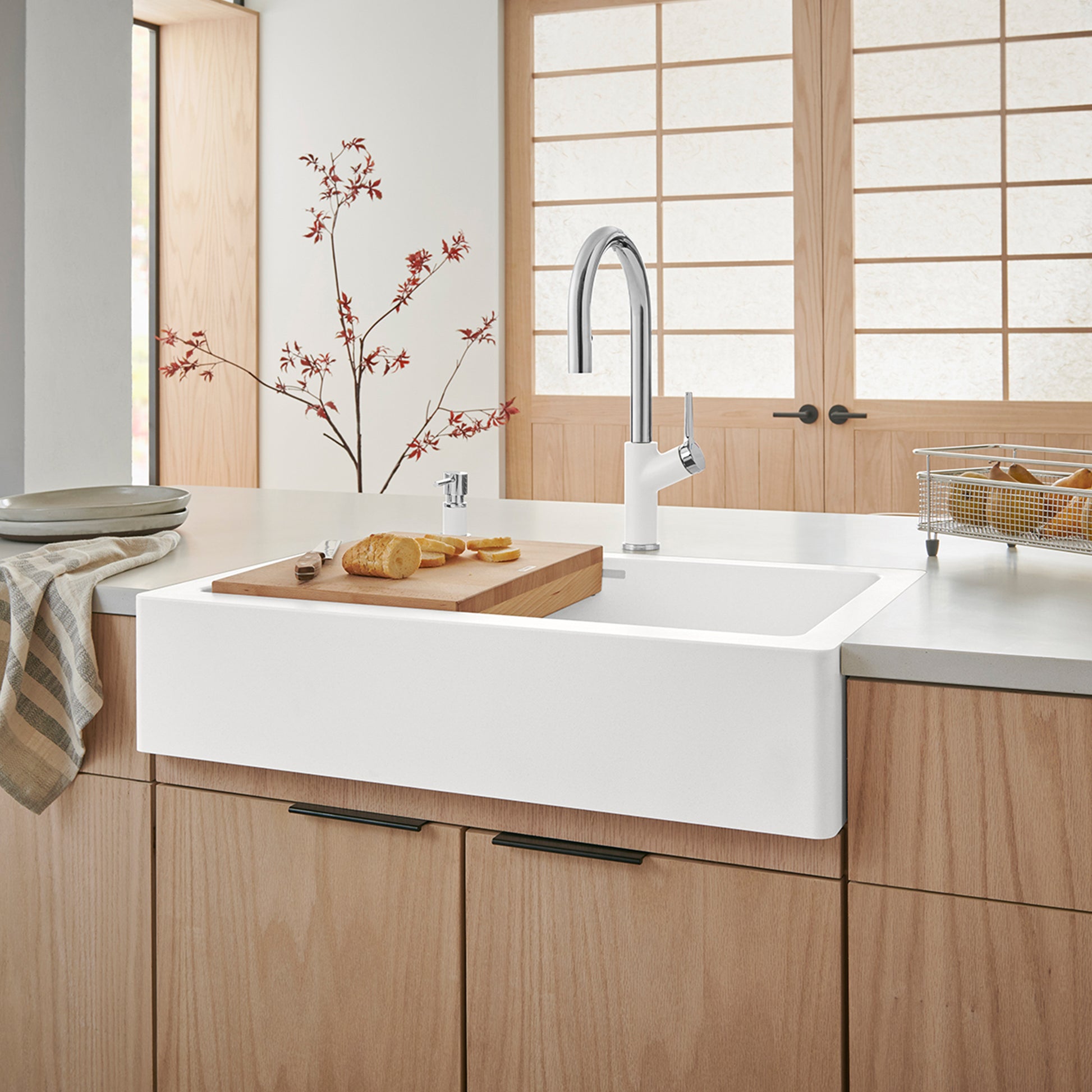 White apron farmhouse sink mounted on wood cabinetry with chrome pull-down faucet in kitchen setting.