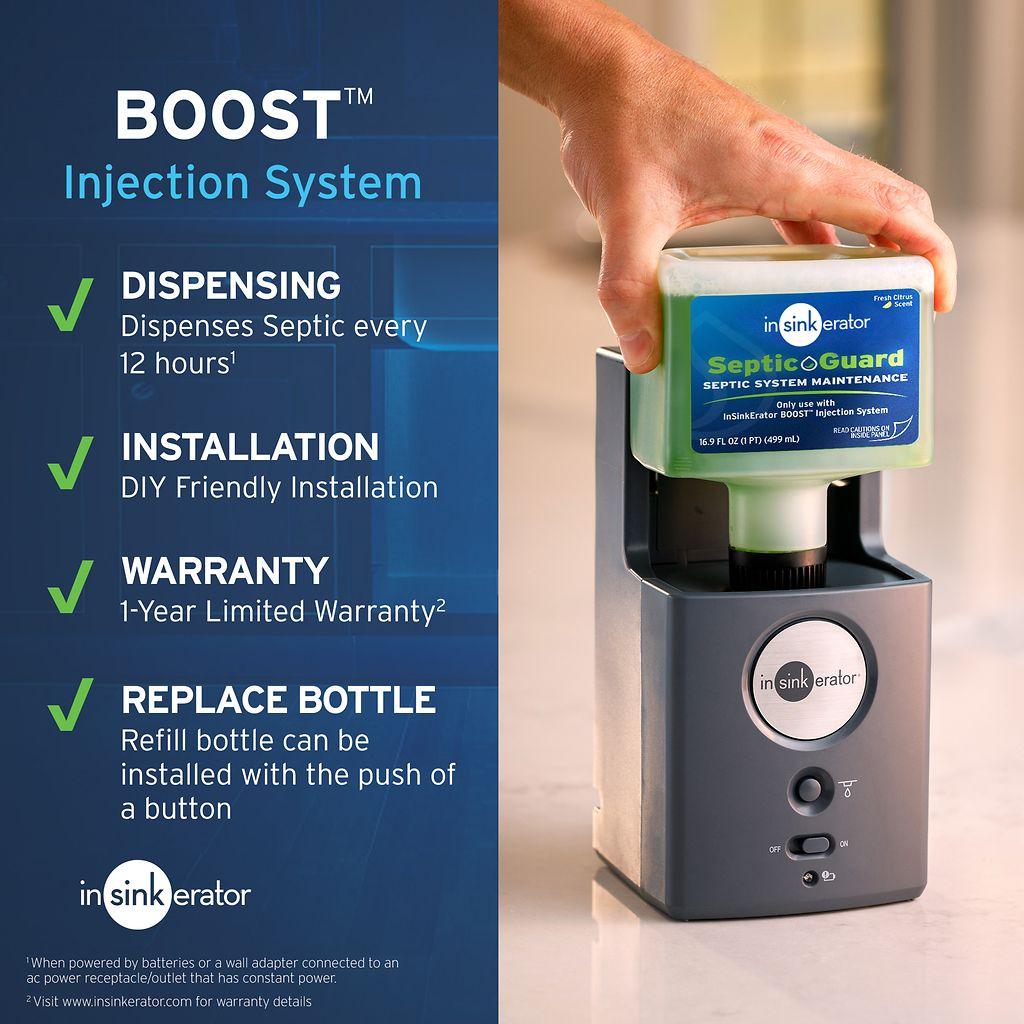 Hand holding green Septic Guard refill bottle above black InSinkErator Bio-Charge Boost injection system dispenser unit.