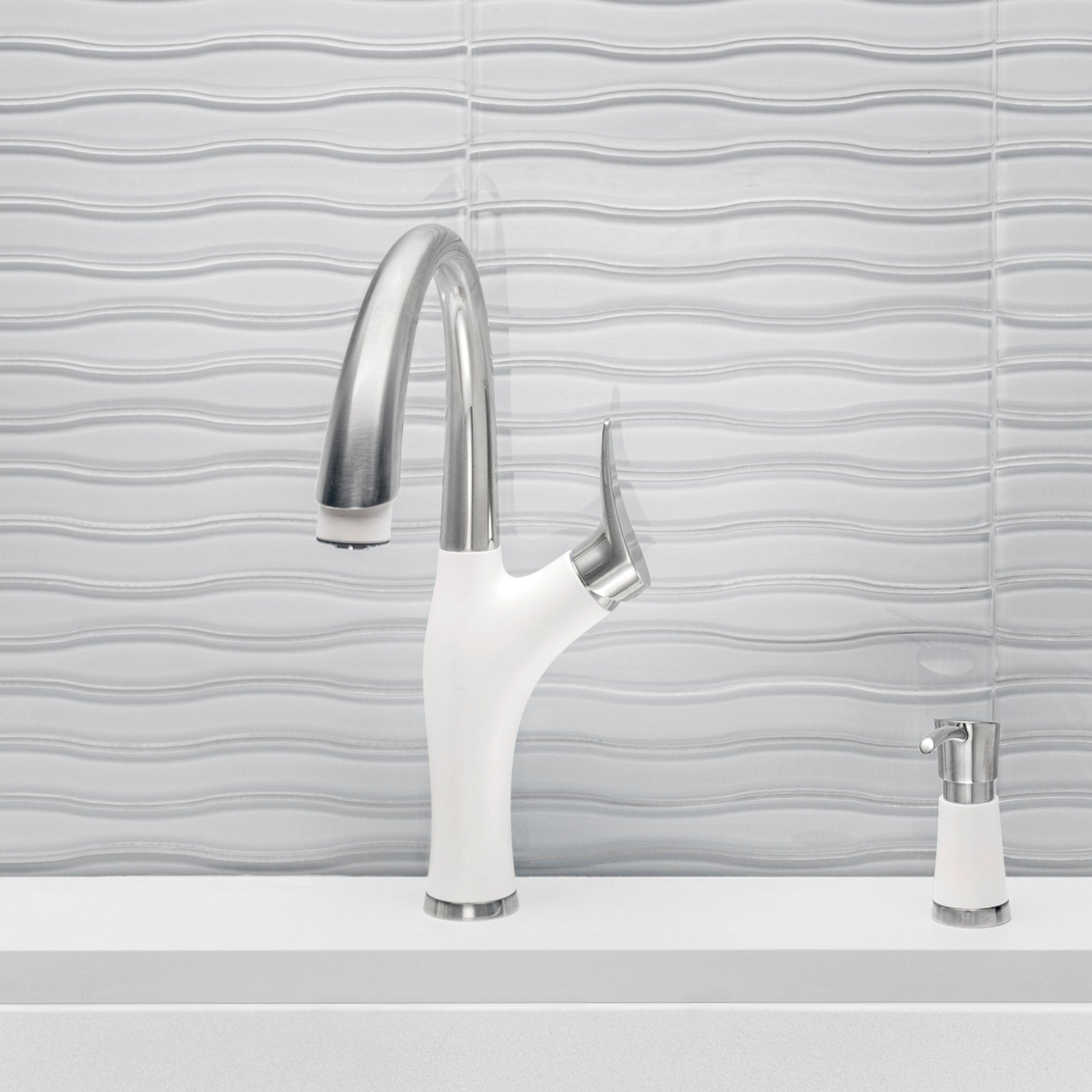 White and stainless steel pull-down kitchen faucet with curved spout and matching soap dispenser on countertop.