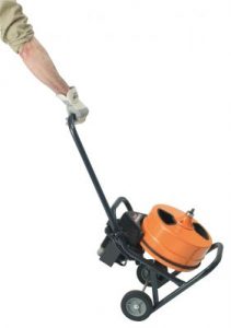 Orange and black motorized drain cleaning machine with wheels and black cable attached to operator's hand.