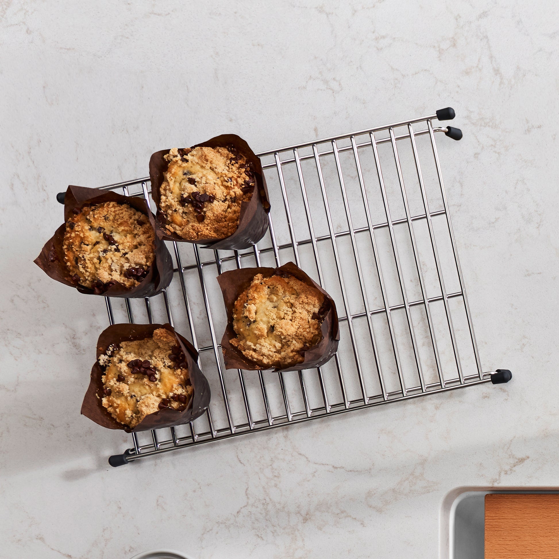 Stainless steel sink grid with rectangular shape and parallel wire design, featuring black rubber feet and four muffins in pa
