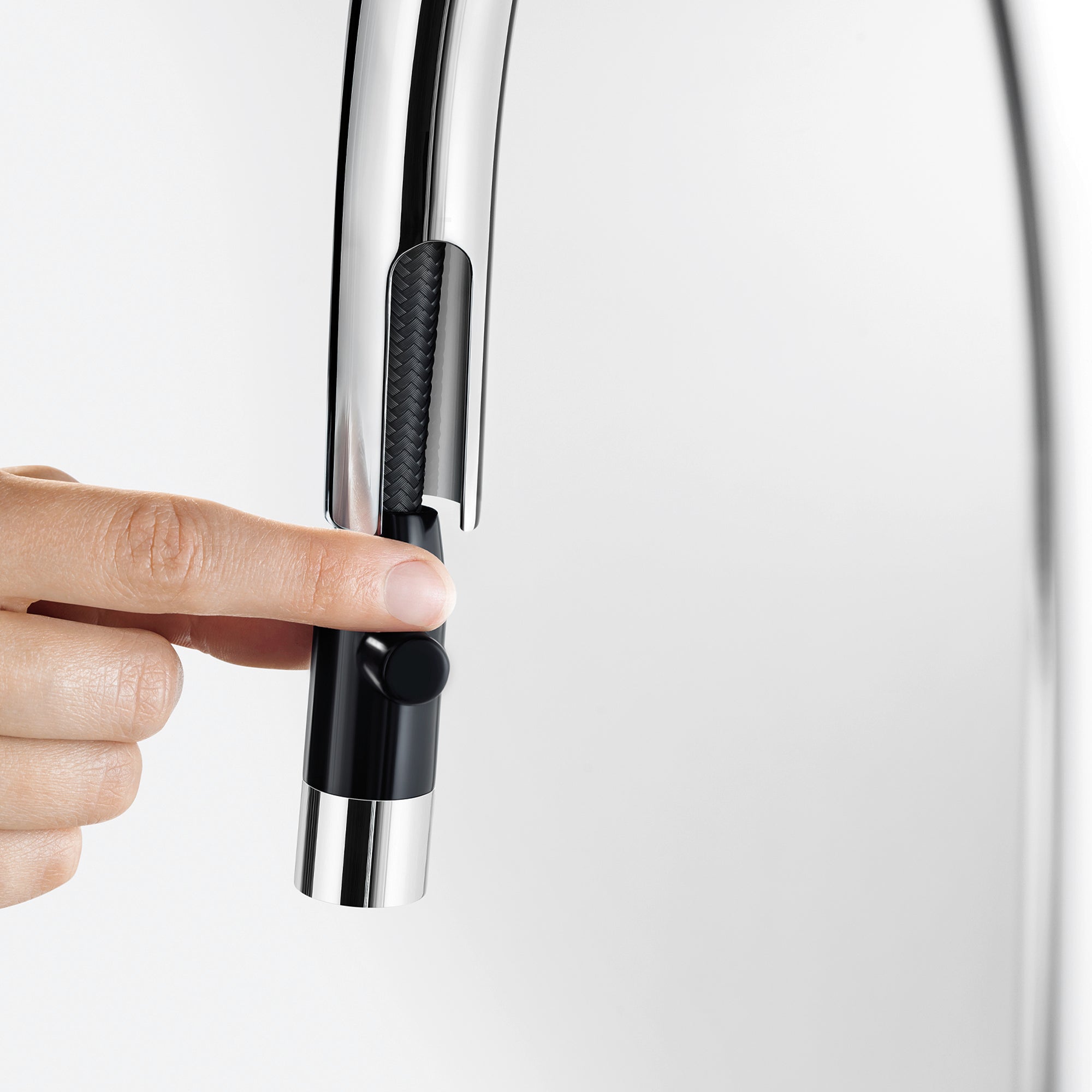 Chrome and black pull-down kitchen faucet spout with textured grip handle held in hand.