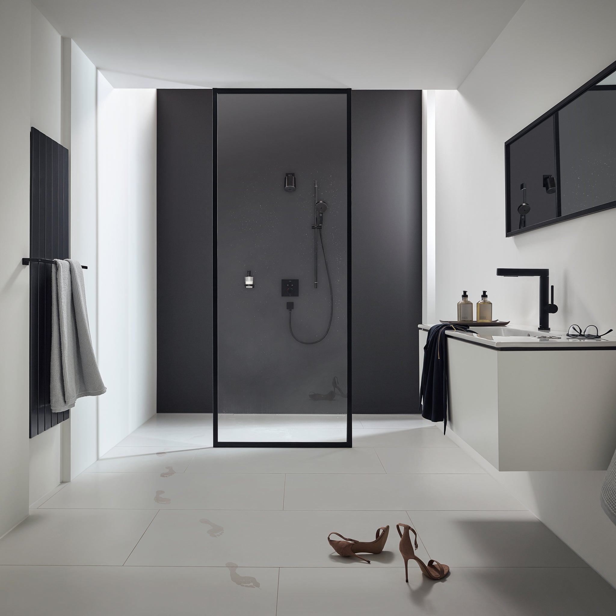 Matte black shower head mounted on dark tile wall inside glass-enclosed shower enclosure.