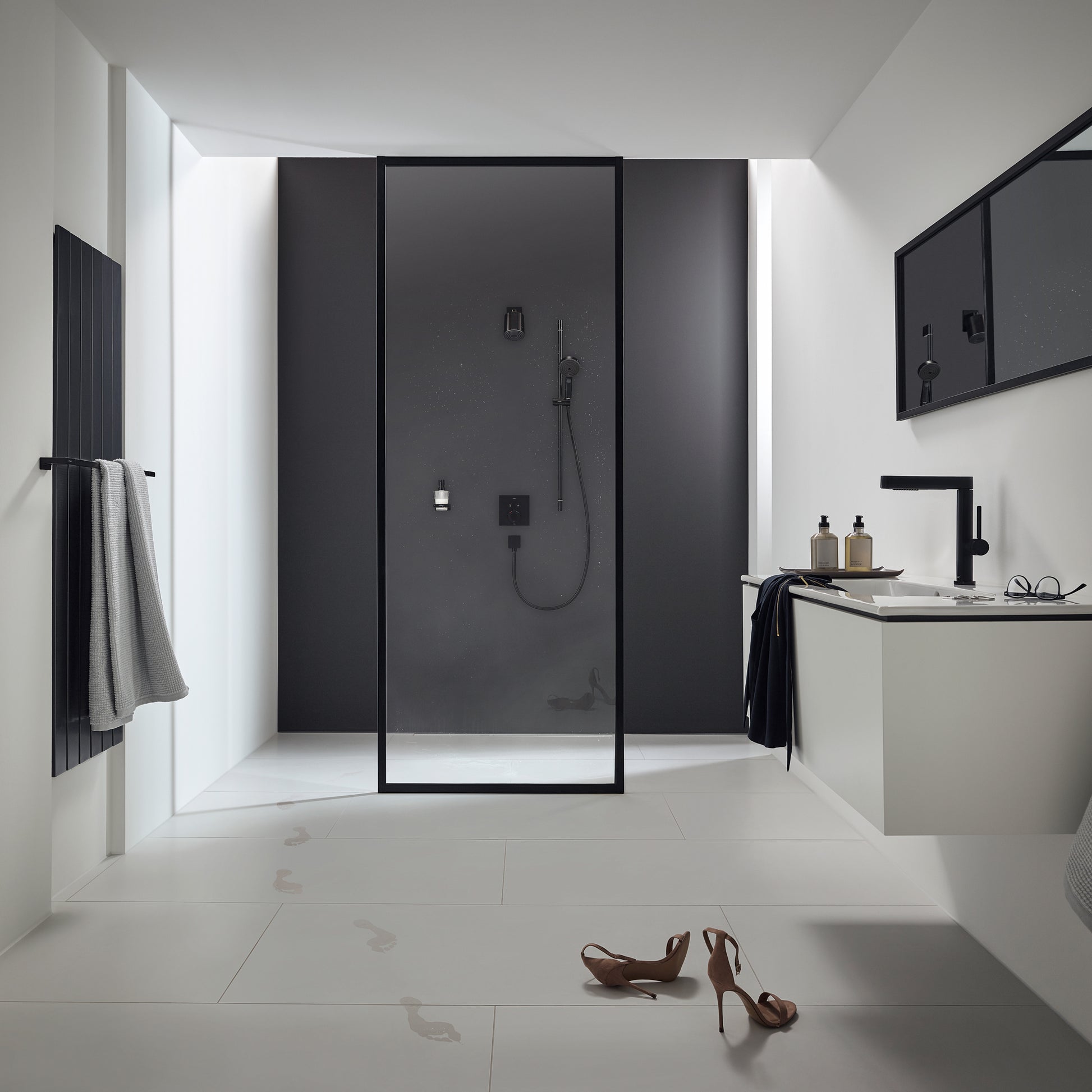 Matte black single-jet shower head mounted on dark wall panel inside glass-enclosed shower enclosure.