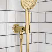 Brushed gold handshower holder with outlet mounted on tile wall, featuring round perforated showerhead and angled valve lever