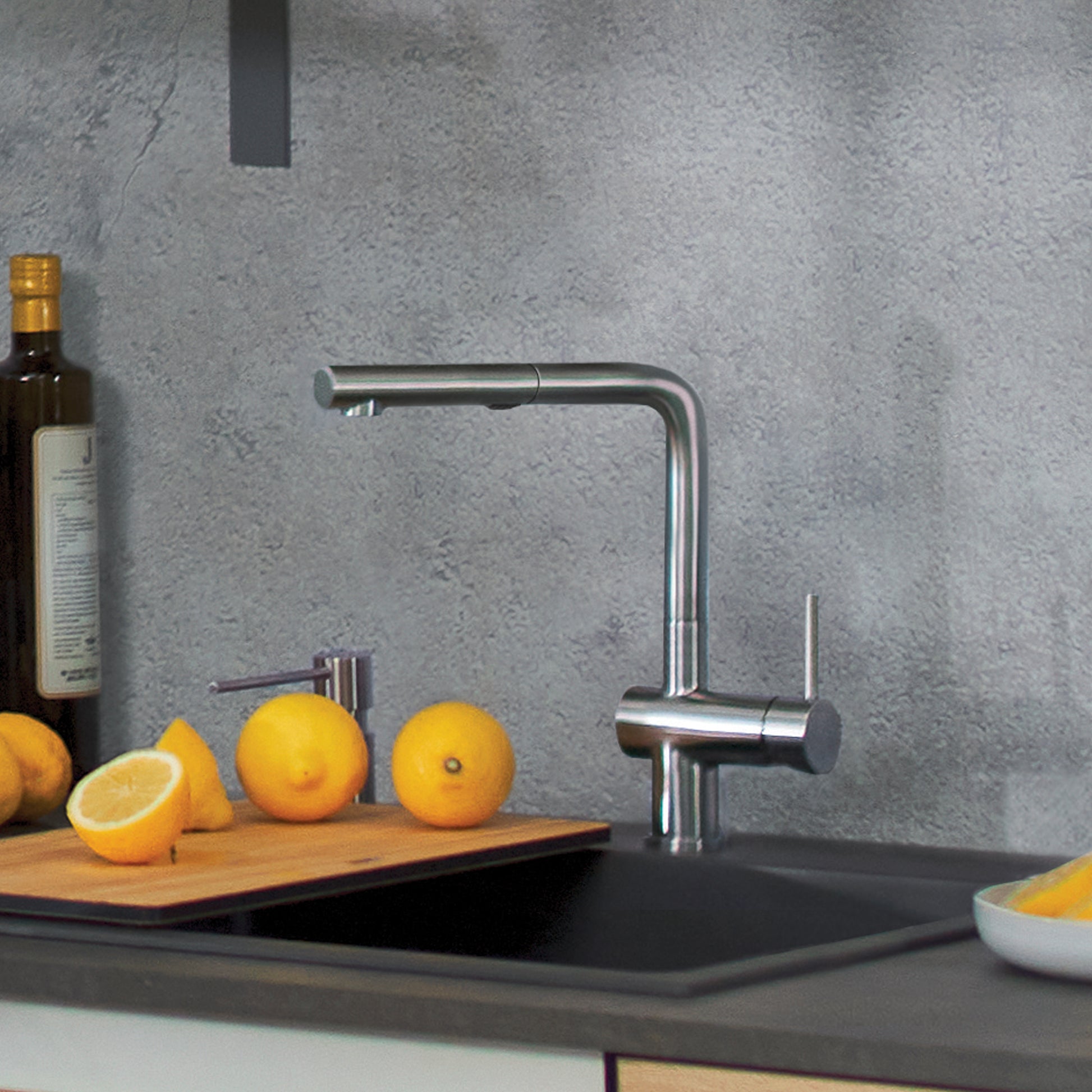 Stainless steel pull-out kitchen faucet with high arc spout installed above black sink, shown with lemons and wine bottle.