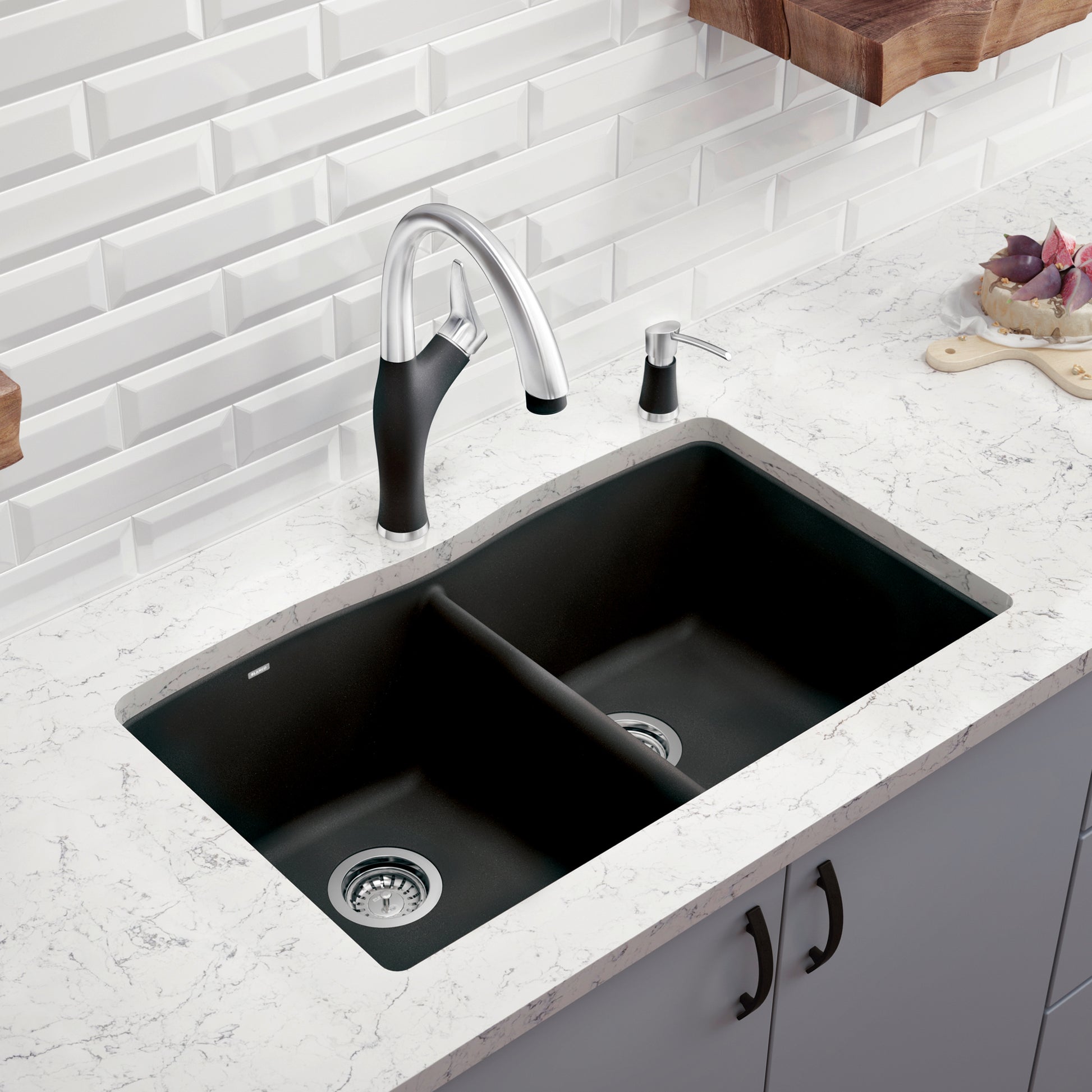 Anthracite double bowl undermount kitchen sink with chrome faucet and soap dispenser installed in white countertop.