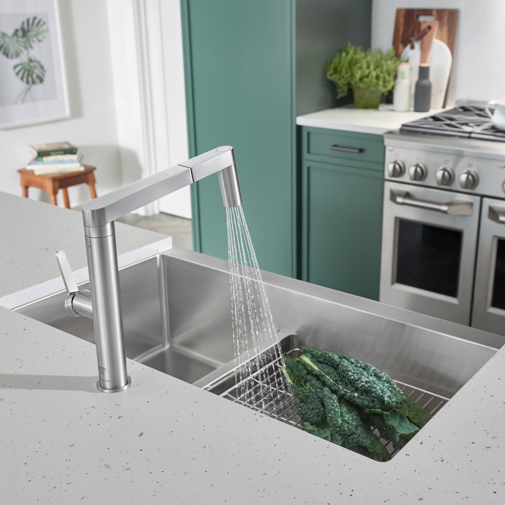 Stainless steel two-basin apron sink with low divider and articulating faucet in kitchen countertop.