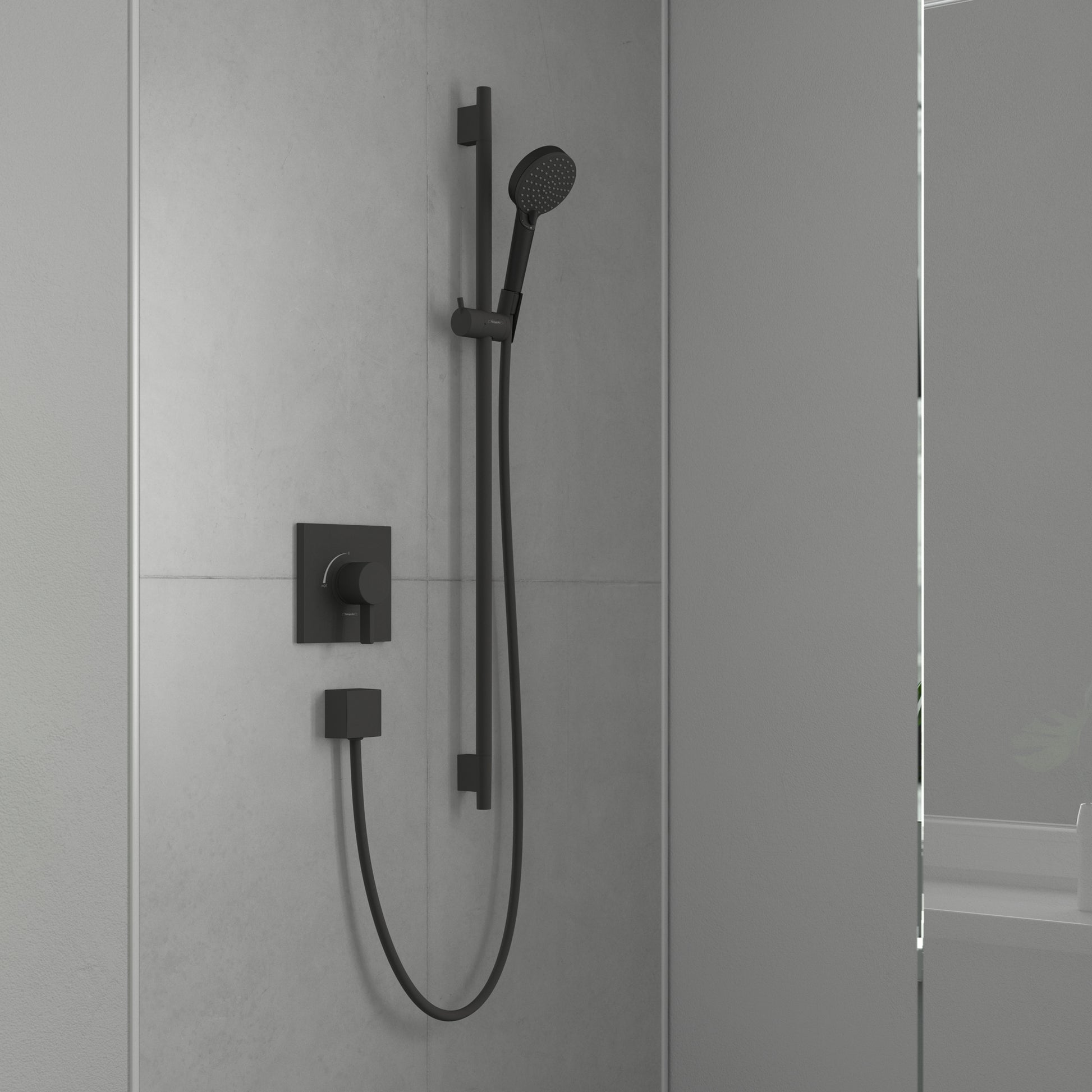 Matte black wall-mounted shower system with square valve trim, handheld showerhead on vertical bar, and curved hose connectio