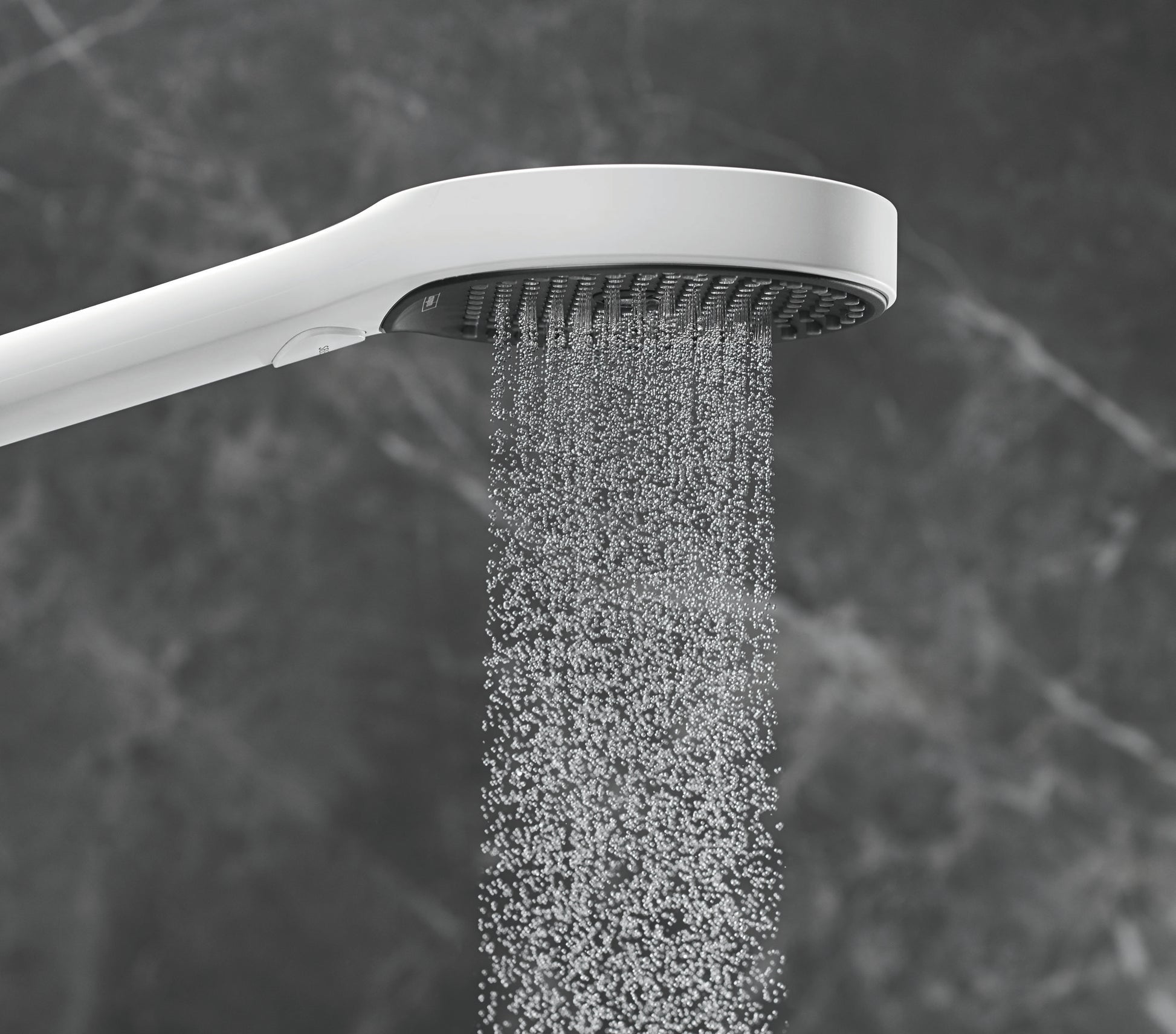 Matte white handheld showerhead with curved arm dispensing water in multiple jets against a dark tile background.