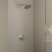 Brushed nickel shower set with round overhead showerhead and wall-mounted control valve on tiled bathroom wall.