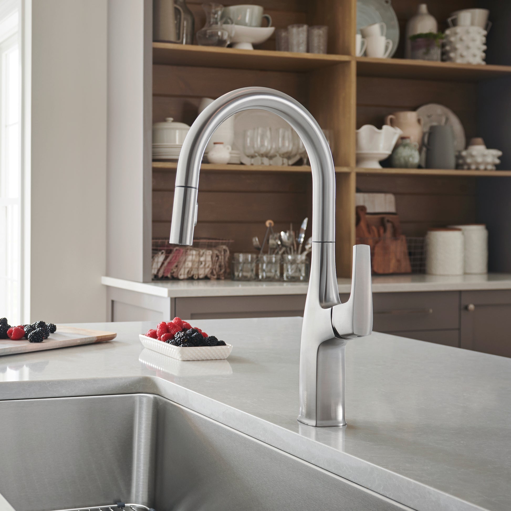 Stainless steel pull-down kitchen faucet with curved spout and single lever handle mounted above sink.