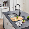 Gray composite cutting board with integrated sink area next to modern kitchen faucet and white cabinetry.