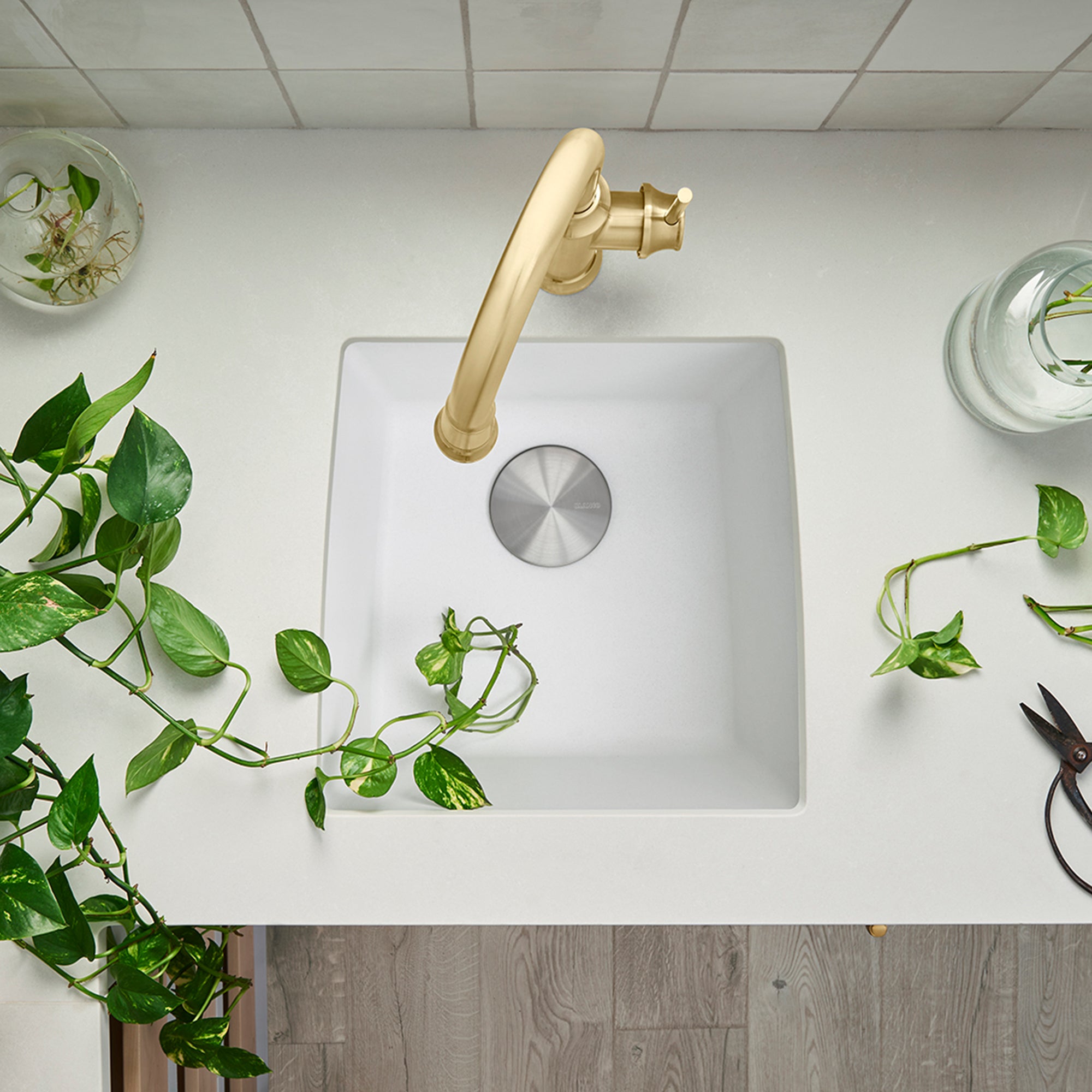 White square undermount kitchen sink with single bowl and brushed gold faucet, viewed from above.