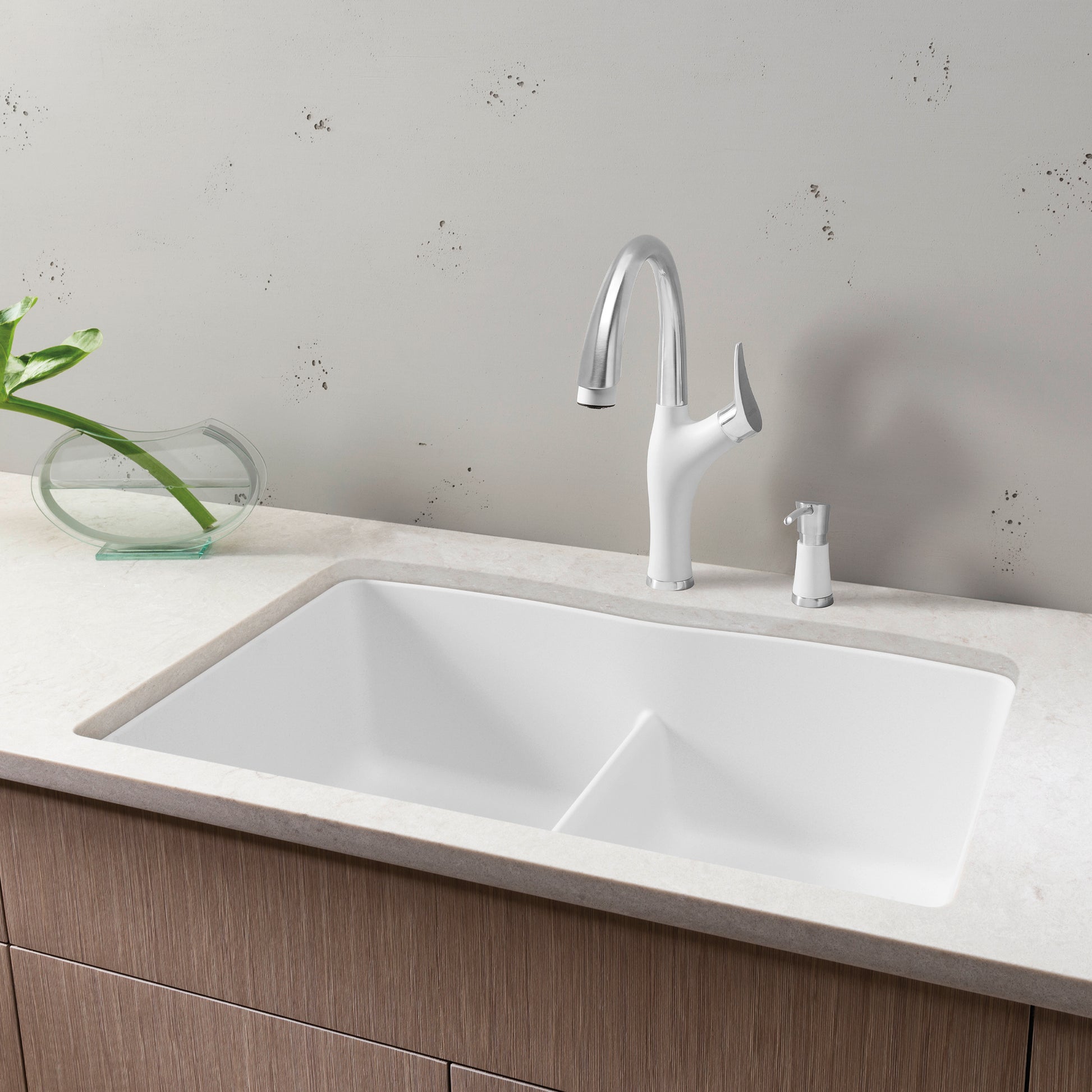 White double bowl undermount sink with low divider, chrome pull-down faucet, and soap dispenser on marble countertop.