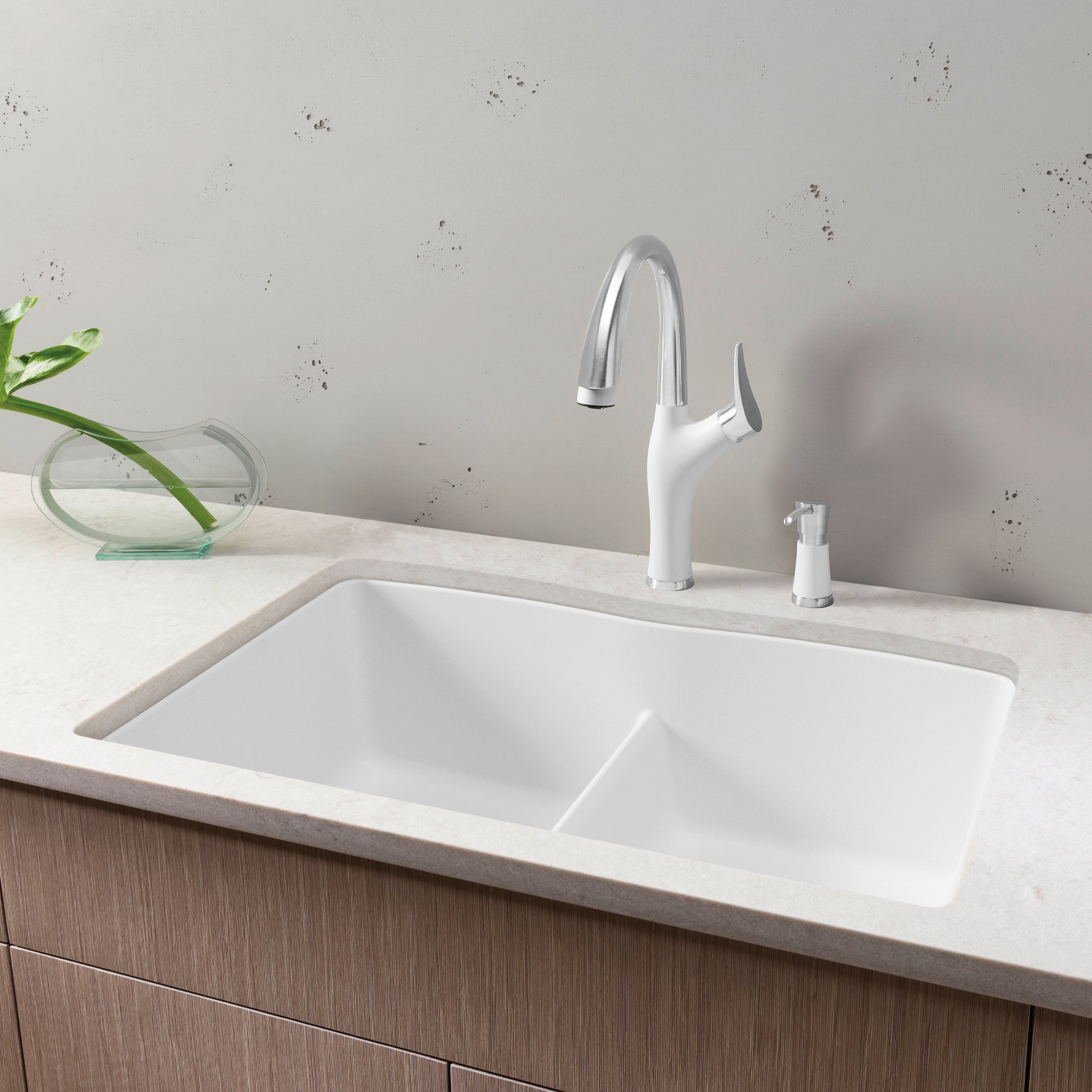 White double bowl undermount sink with low divider, chrome pull-down faucet, and soap dispenser on marble countertop.