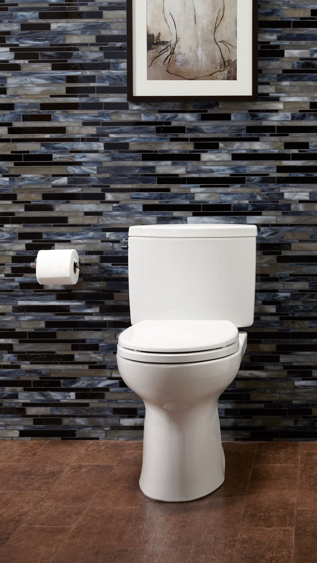 White two-piece round toilet with closed seat and tank against blue and black tile wall with toilet paper holder.