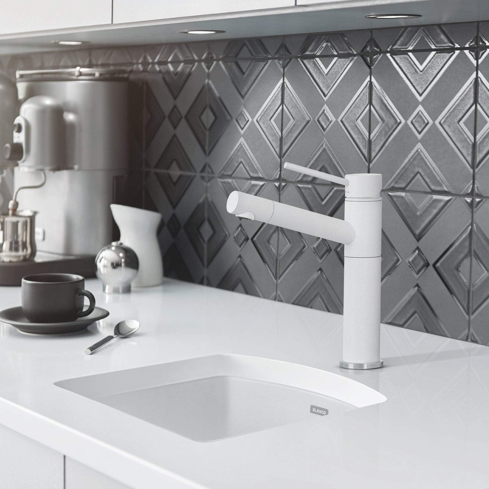White rectangular drop-in kitchen sink with rounded corners installed in white countertop, paired with white pull-out faucet.