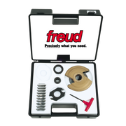 Black plastic Freud case containing tan and black router bit components, metal rings, spacers, and a red wrench tool.