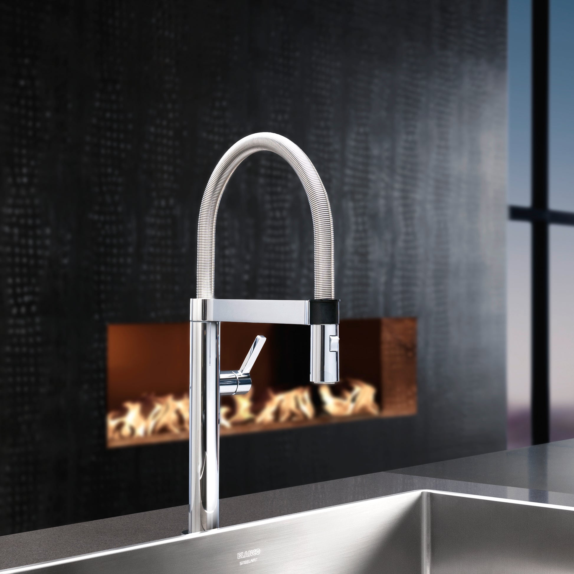 Chrome pull-down kitchen faucet with curved spout and flexible hose, installed above stainless steel sink.