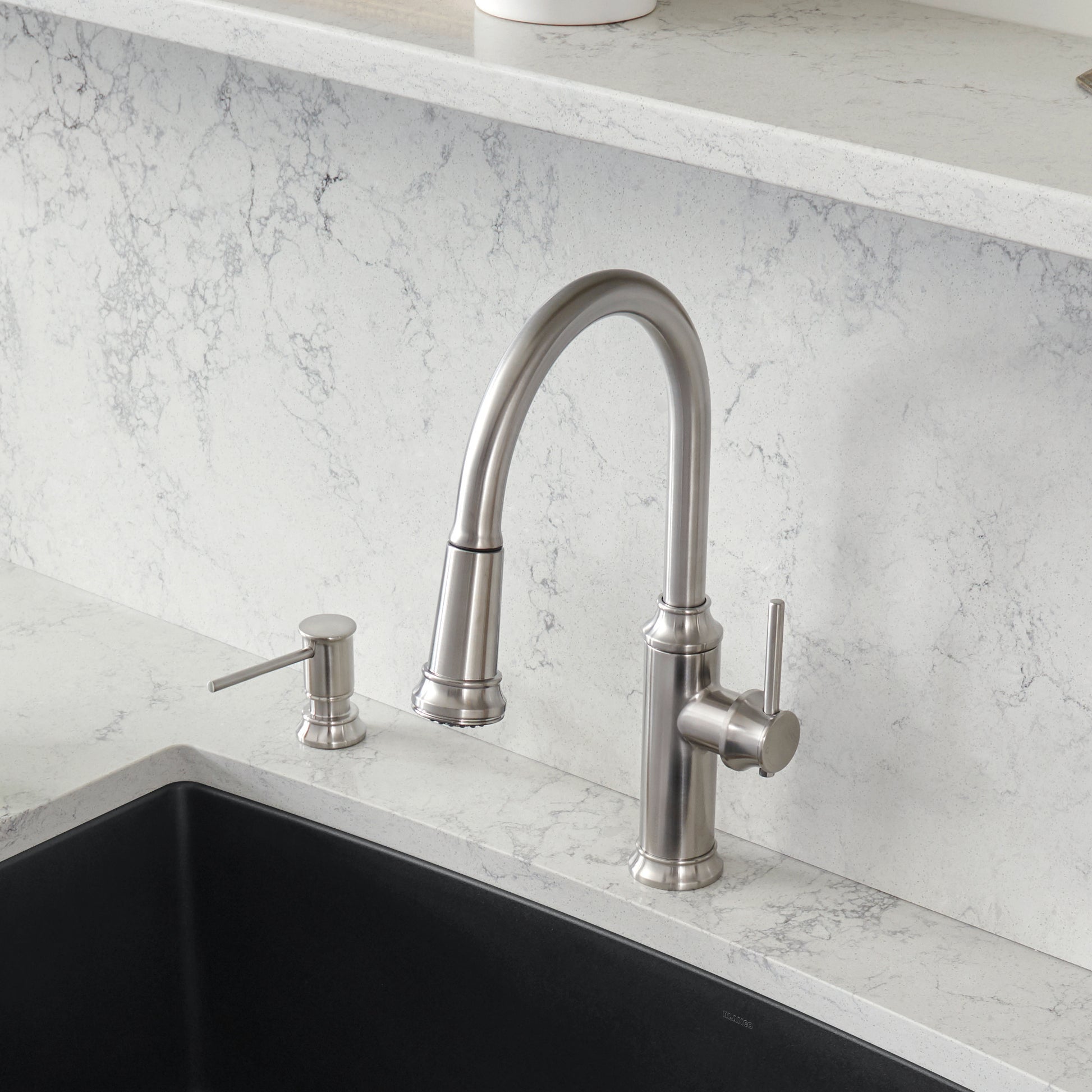 Stainless steel pull-down kitchen faucet with curved spout and matching soap dispenser on marble countertop.