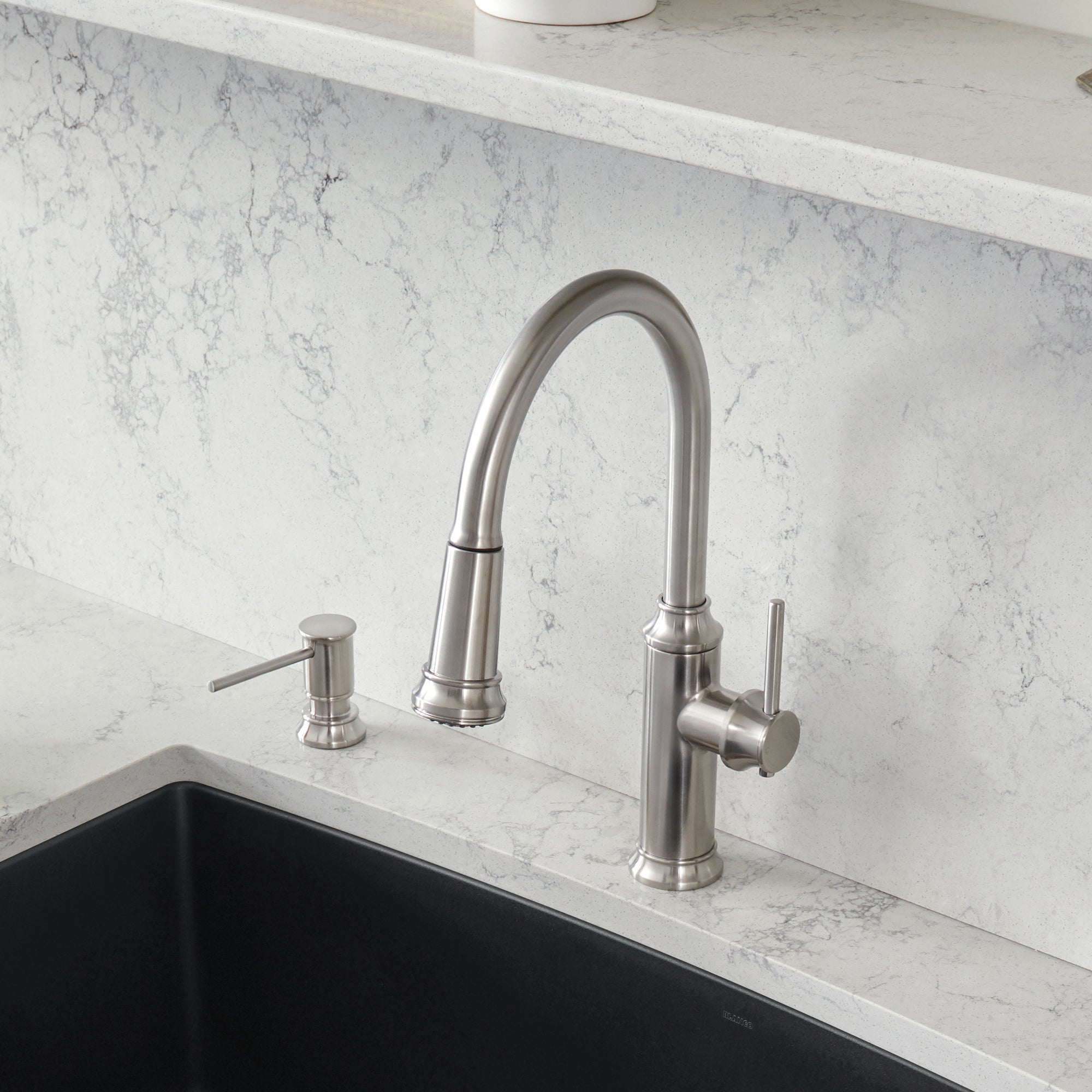 Stainless steel pull-down kitchen faucet with curved spout and matching soap dispenser on marble countertop.